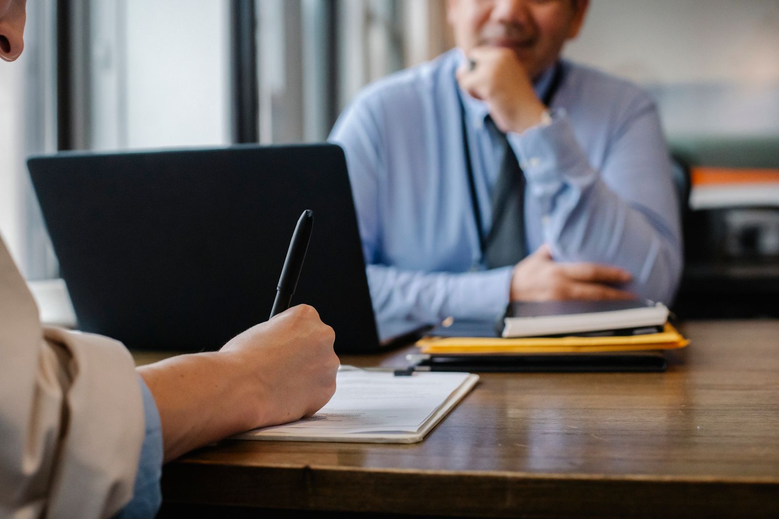 A solicitor meeting a client across a desk and taking notes