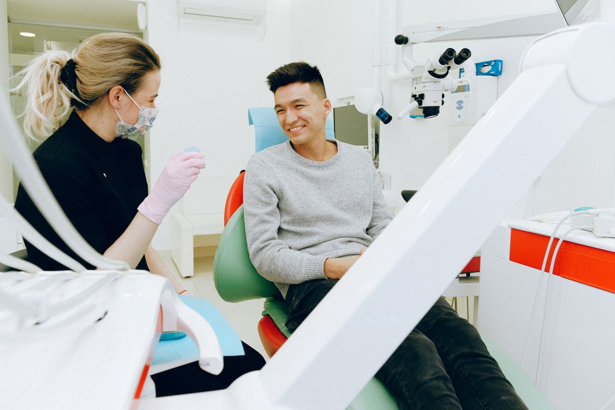 A dentist talking with a patient in a treatment room